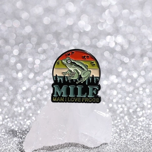 Detail of MILF Man I Love Frogs enamel pin with sunset and forest on crystal base