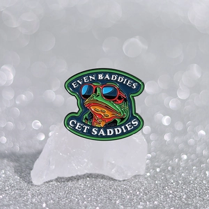 Green frog enamel pin with red sunglasses and Even Baddies Get Saddies slogan