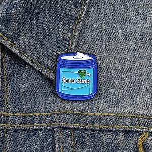 Detail of Sana Sana blue enamel jar pin on a denim jacket collar with gold stitching