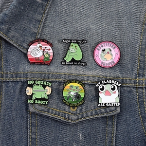 Detail of funny cartoon frog enamel pins with slogans on blue denim jacket