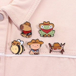 Close-up of five cute cowboy animal enamel pins styled on a pink denim jacket collar