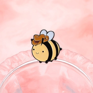 Cartoon-Bienen-Emaille-Anstecknadel mit Cowboyhut auf weichem rosa Hintergrund