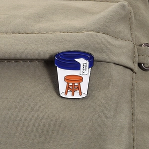 Detailed close-up of a funny stool sample enamel pin on a khaki canvas background