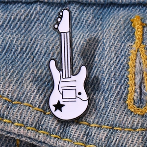 Detail of white electric guitar enamel pin with black star on denim fabric jacket