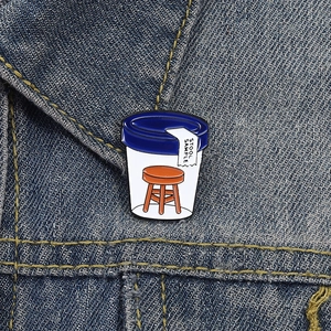 Macro view of Stool Sample enamel pin badge featuring a funny stool medical jar on denim
