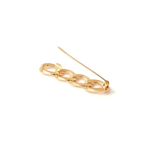 Detailed view of a gold Cuban link chain brooch with a polished finish and back pin