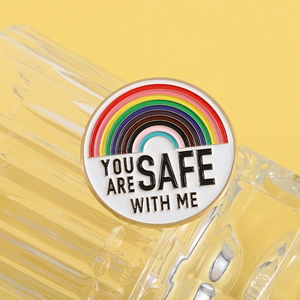 Vue macro de l'épingle émaillée arc-en-ciel You Are Safe With Me sur fond de verre