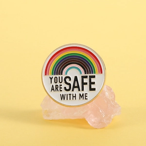 Pin's arc-en-ciel en émail You Are Safe With Me sur fond esthétique rose et jaune
