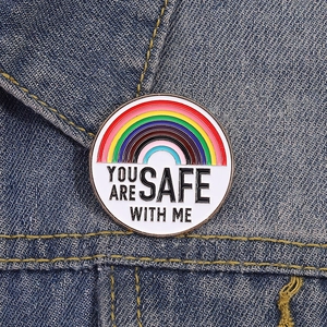 Rainbow enamel pin with YOU ARE SAFE WITH ME message on blue denim jacket texture