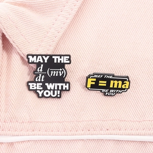Close-up of physics formula enamel pins featuring F=ma and d/dt(mv) on denim fabric