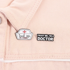 Detail of creative enamel nurse hat brooch and doctor badge pinned on denim fabric