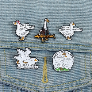 Detail of five funny white goose enamel pins on denim fabric with cyberpunk motifs