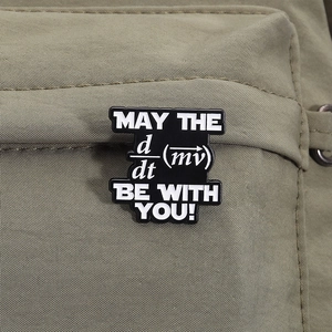 Macro shot of black enamel physics badge with force formula on green canvas bag