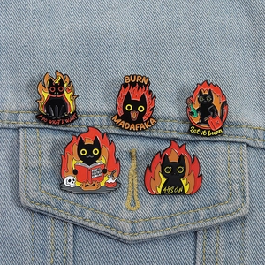 Detailed view of black cat enamel pins with flame designs on blue denim jacket