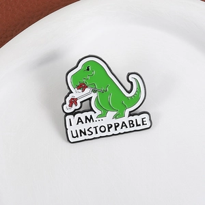 Cartoon green dinosaur enamel pin with 'I AM UNSTOPPABLE' quote for clothing and backpacks