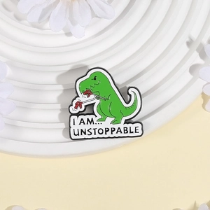 Funny green dinosaur enamel pin with Unstoppable quote on white decorative display