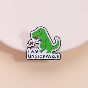 Cute green dinosaur enamel brooch pin with Unstoppable text on a display stand