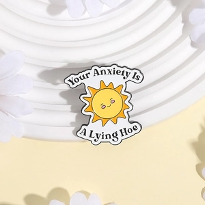 Broche soleil en émail avec texte Your Anxiety Is A Lying Hoe sur plateau blanc
