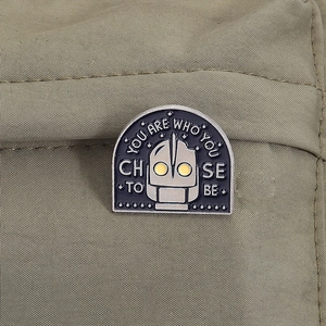 Close-up of Iron Giant enamel pin with inspirational quote on khaki canvas bag