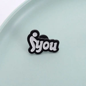 Makroaufnahme der Emaille-Anstecknadel mit Strichmännchen-Motiv und 'YOU' Schriftzug