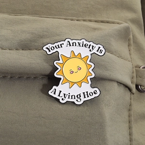 Gros plan d'un pin's émaillé soleil avec slogan sur un sac à dos en toile
