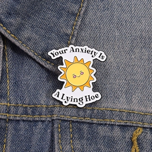 Broche en émail tournesol avec texte anti-anxiété sur fond en tissu denim bleu foncé