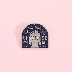 Robot Iron Giant enamel pin with 'You Are Who You Choose To Be' quote on pink background