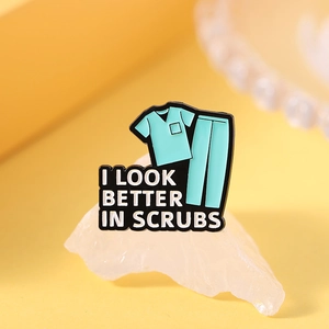Detail of mint green enamel medical scrub pin with text I Look Better In Scrubs