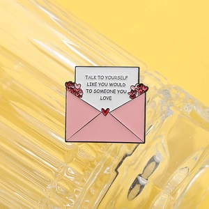 Spilla a busta in smalto rosa con frase motivazionale e cuoricini su sfondo giallo