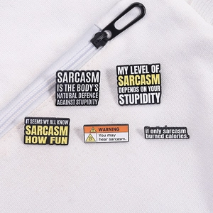 Close-up of five colorful enamel sarcasm pins on white textured fabric with a zipper