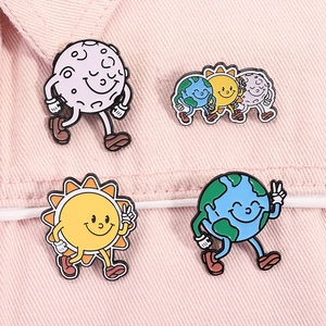 Detailed view of cute cartoon earth sun and moon enamel pins on pink denim fabric