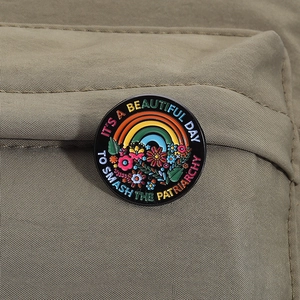 Rainbow and flower enamel pin featuring 'Smash the Patriarchy' quote on canvas background