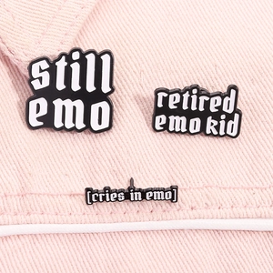Detailed view of emo culture enamel pins with black and white text on pink denim fabric