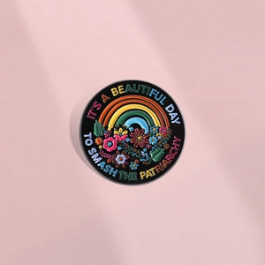 Rainbow flower enamel pin with Smash The Patriarchy quote on a pink background