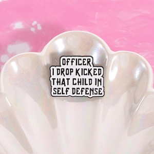 Detail of enamel badge with humor quote on a white shell tray over pink background