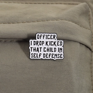 Detail of enamel badge with black humor quote pinned on olive green canvas jacket