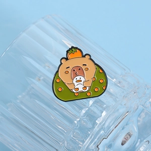 Detailed view of cute Capybara enamel pin with orange and penguin on blue background