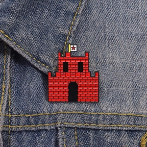 Macro shot of red cartoon castle enamel pin with star flag on blue denim fabric