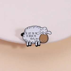 Lindo broche de oveja esmaltado con cita religiosa sobre una bandeja blanca redonda