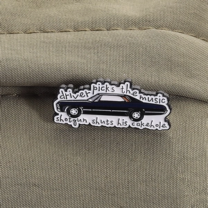 Detailed close-up of supernatural black muscle car enamel pin on green canvas fabric