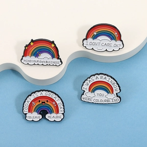 Detailed close-up of rainbow enamel pins with cloud base on blue background