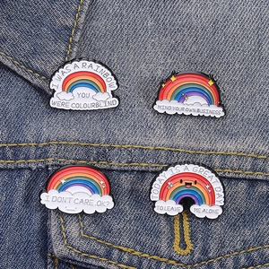 Colorful rainbow enamel pins set with inspiring quotes pinned on blue denim fabric