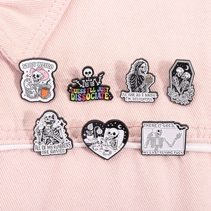 Detailed flat lay of spooky skull enamel pins set on a textured pink denim background