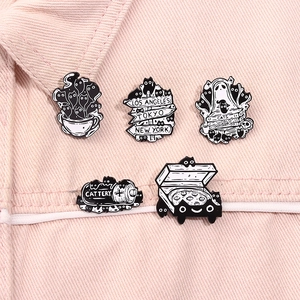 Detailed close-up of 5-piece black and white cartoon cat enamel pins on pink denim fabric