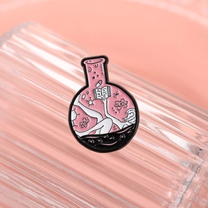Detail of pink science flask enamel pin featuring reading person and atomic molecules