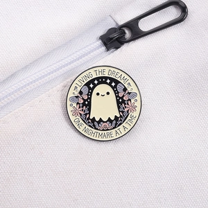 Detalle del broche de fantasma con flores y texto decorativo en una mochila de tela