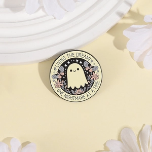 Pin de esmalte de fantasma con flores y frase 'Living the Dream' sobre base amarilla