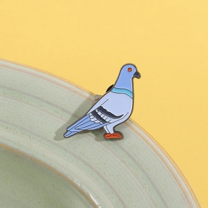 Detail der farbenfrohen Tauben-Brosche mit buntem Emaille auf einem grünen Keramikständer