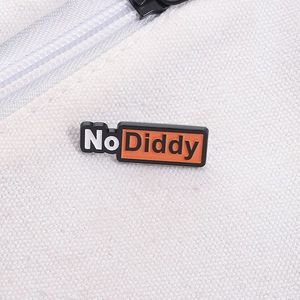 Détail macro du pin's rectangulaire en émail 'No Diddy' sur une toile blanche