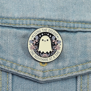 Detalle del pin esmaltado de fantasma lindo con flores sobre bolsillo de mezclilla